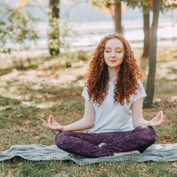 Woman meditating peacefully in a natural setting.