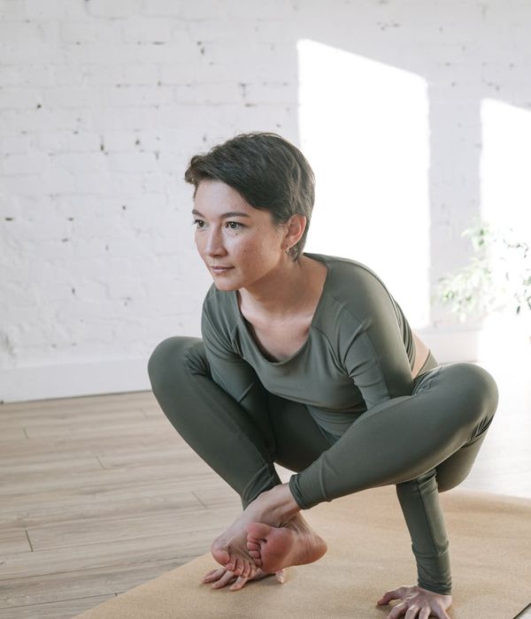 Woman performing a gentle yoga pose in a bright, calm room.